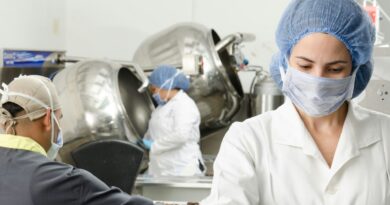 three people inside factory wearing masks and coats