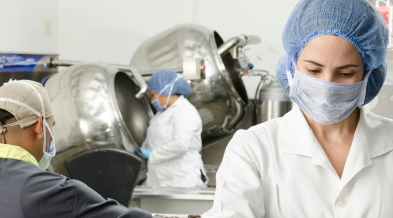 three people inside factory wearing masks and coats